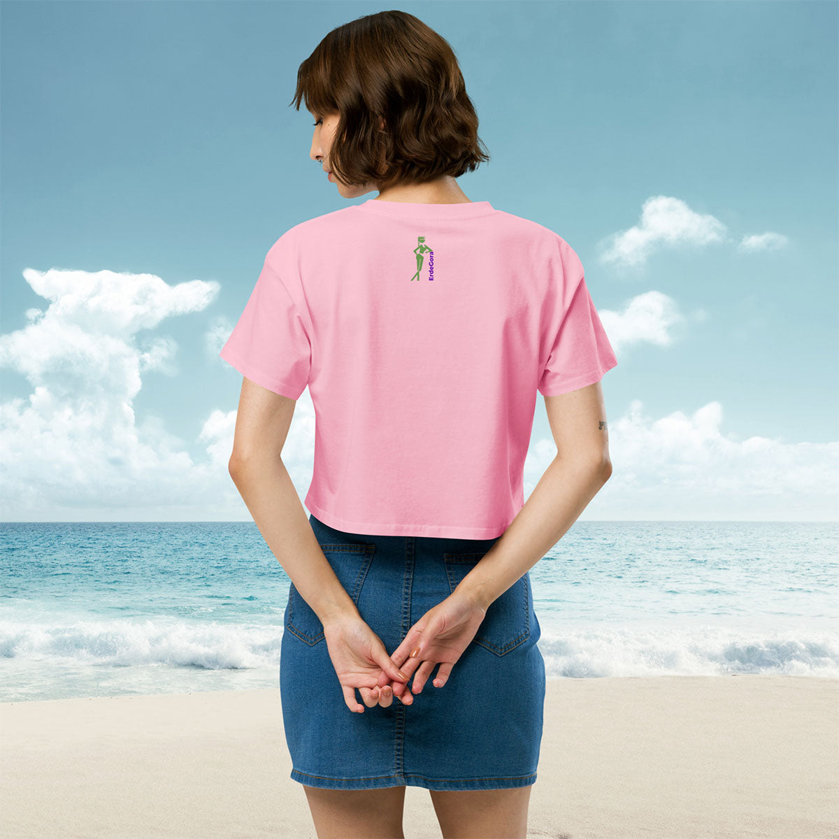 Woman wearing a pink t-shirt erdegora logo, posing on a beach, back view