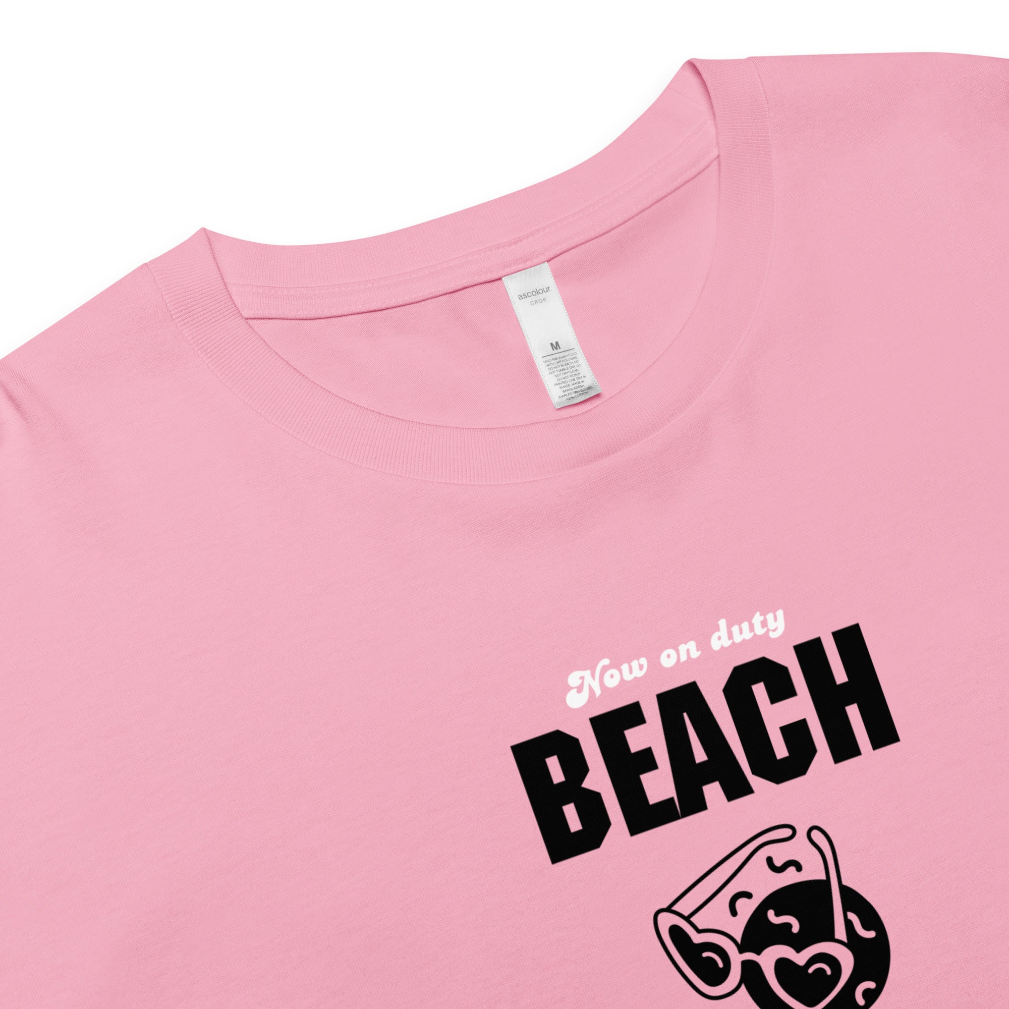 Pink t-shirt with 'Now on duty BEACH' text and sunglasses graphic, crewneck detail, close up