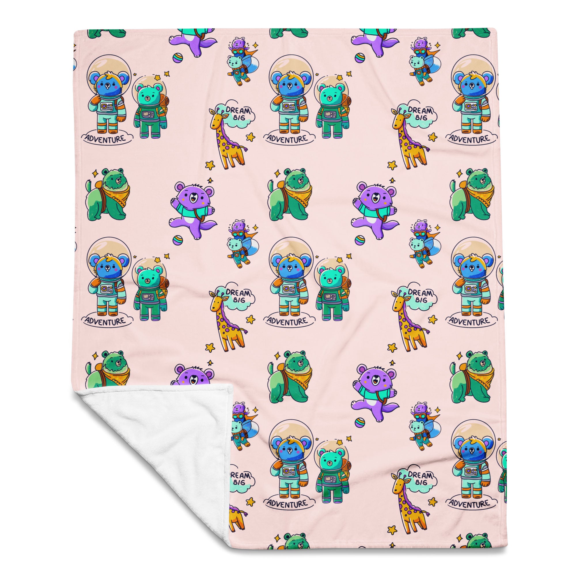 Flat-lay of a pale pink throw blanket printed with cute cartoon astronaut bears, koalas, giraffes and “Dream Big Adventure” text, with one corner folded to reveal the soft white fleece backing.