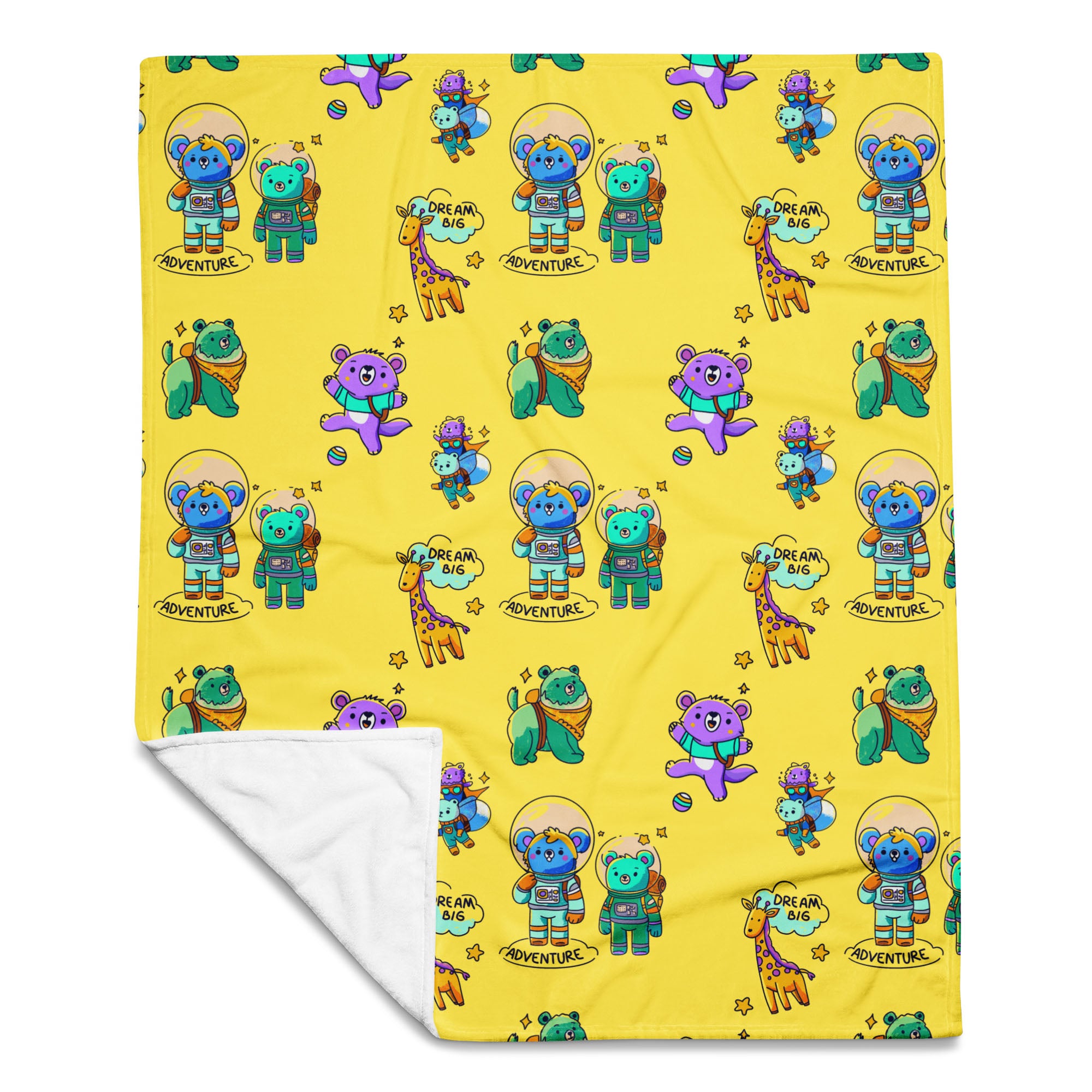 Flat-lay of a yellow throw blanket printed with cute cartoon astronaut bears, koalas, giraffes and “Dream Big Adventure” text, with one corner folded to reveal the soft white fleece backing.