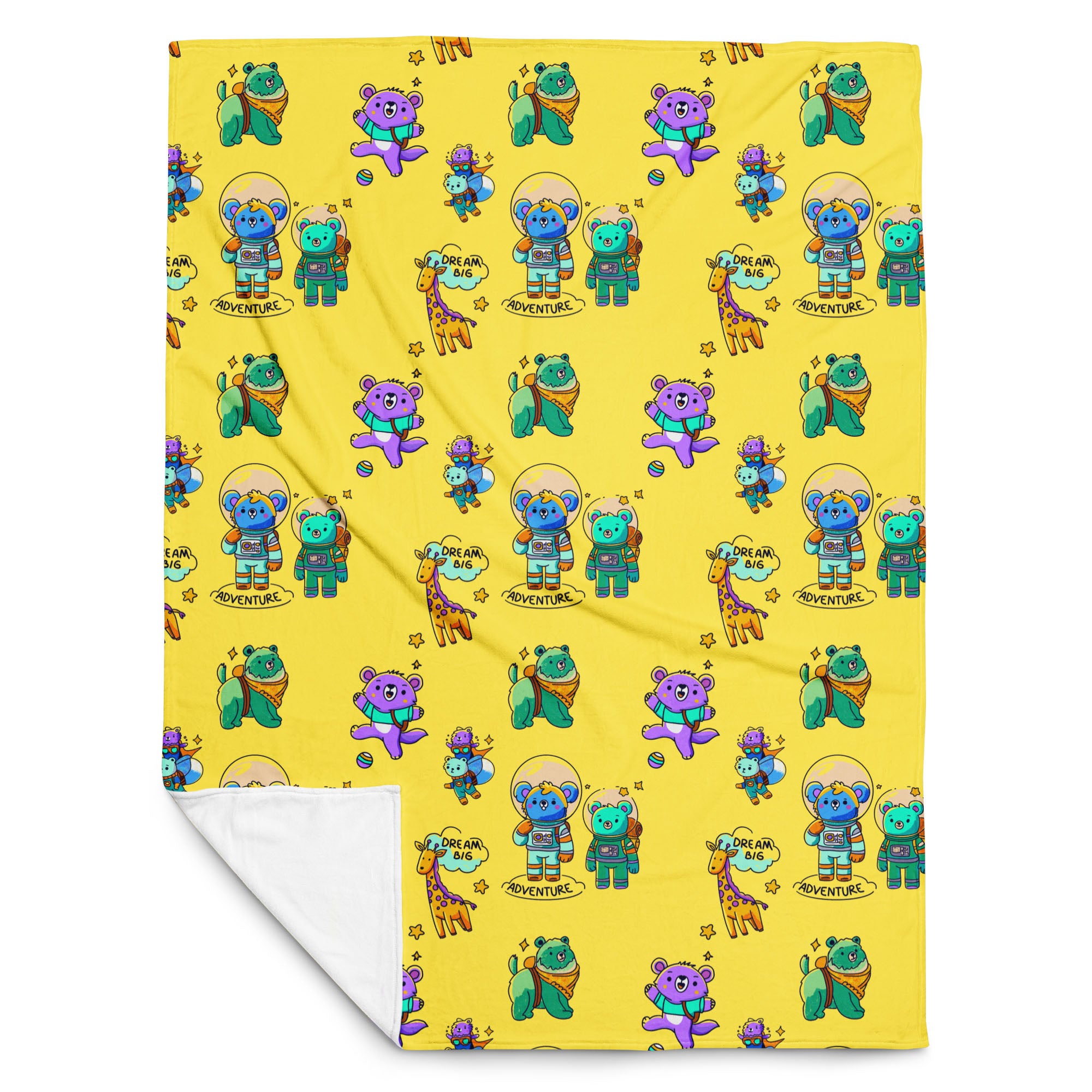 Flat-lay of a yellow throw blanket printed with cute cartoon astronaut bears, koalas, giraffes and “Dream Big Adventure” text, with one corner folded to reveal the soft white fleece backing.