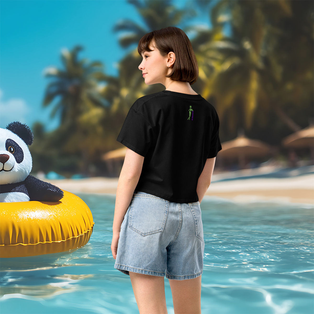 Person standing by the sea with a panda floaty and palm trees in the background.