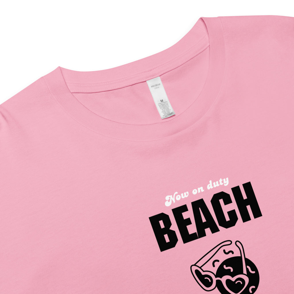 Pink t-shirt with 'Now on duty BEACH' text and sunglasses graphic, crewneck detail, close up