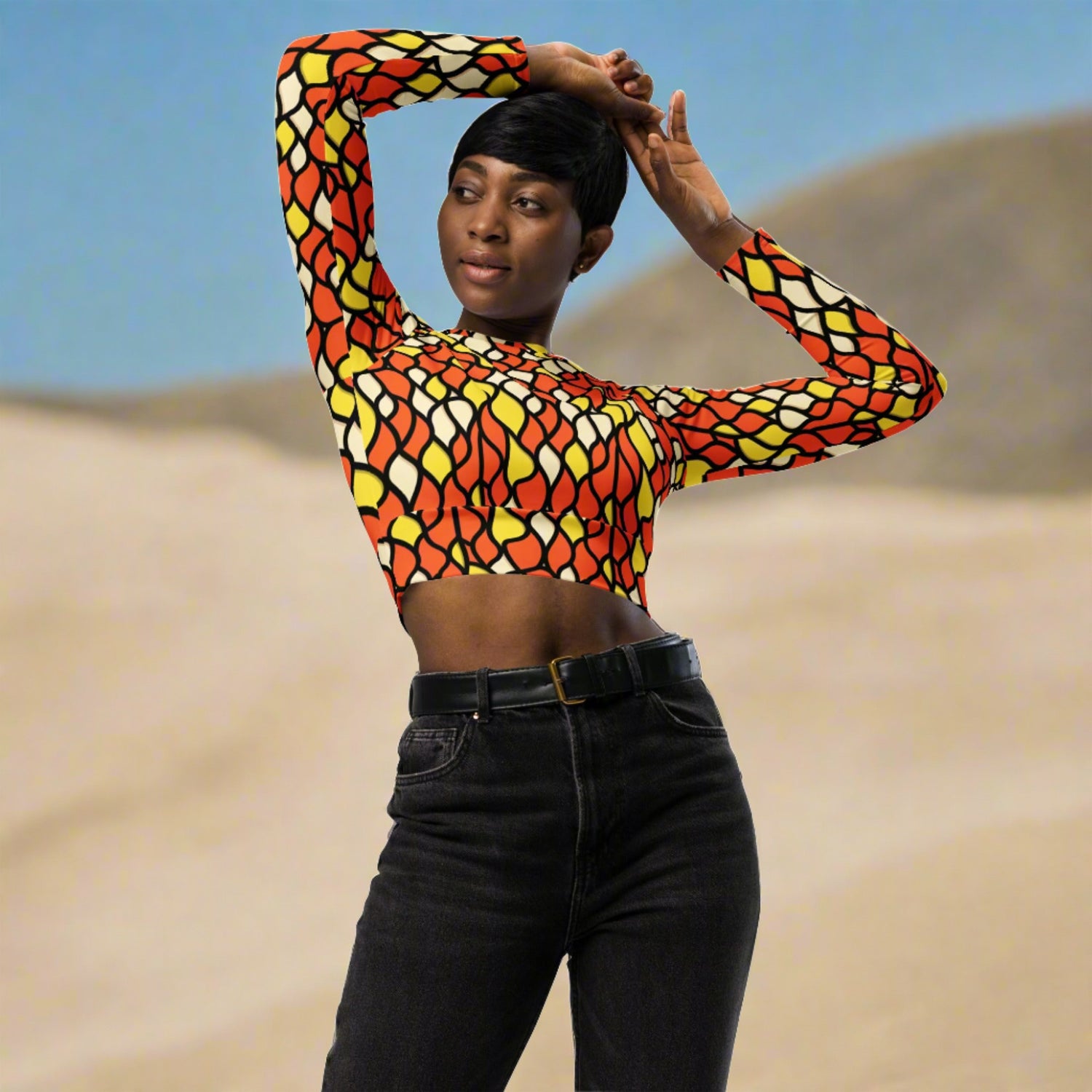 Woman wearing Recycled Long-Sleeve Crop Top in Honeycomb, standing confidently, showcasing the vibrant honeycomb pattern and wide waistline band.