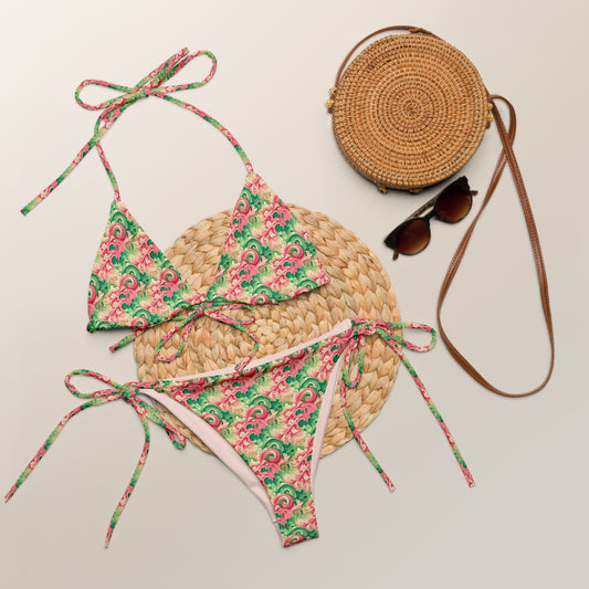 Recycled string bikini with a vibrant floral pattern in pink and green, featuring adjustable ties and eco-friendly materials.