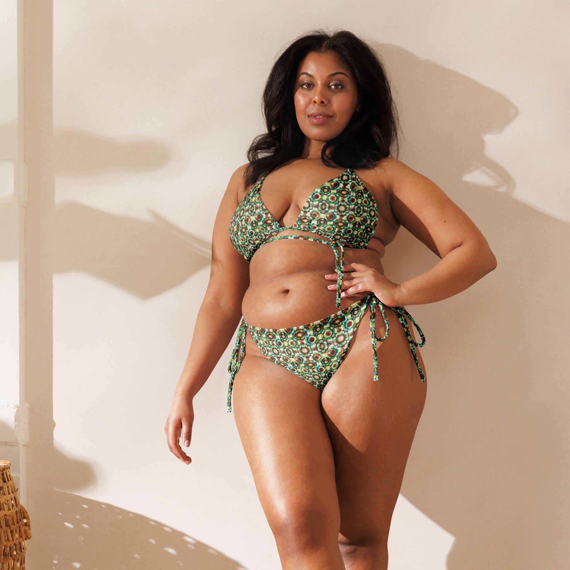 Recycled string bikini with a vibrant kaleidoscopic pattern in green, brown, and teal, featuring adjustable ties and eco-friendly materials.