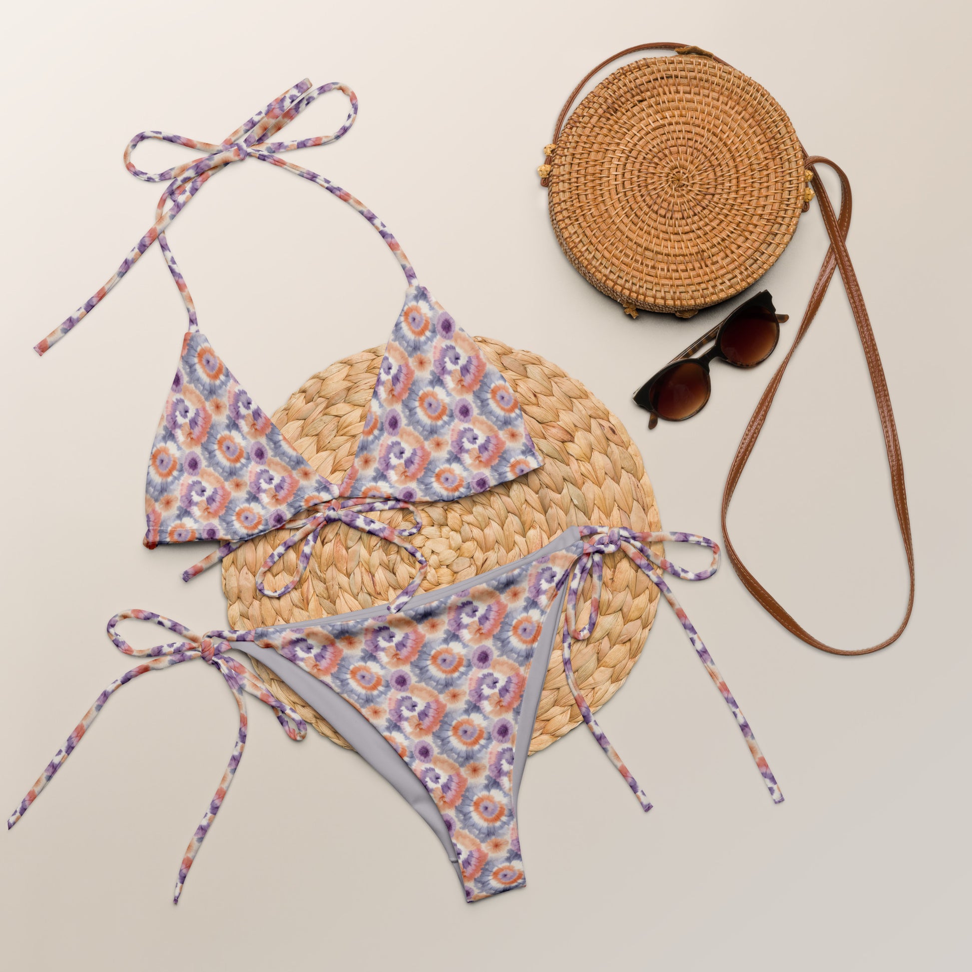 Recycled string bikini with a dreamy tie-dye pattern in lavender, peach, and cream, featuring adjustable ties and eco-friendly materials.