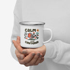 Person holding a white mug with a design of a bird and text 'CALM and CENTERED' on a plain background