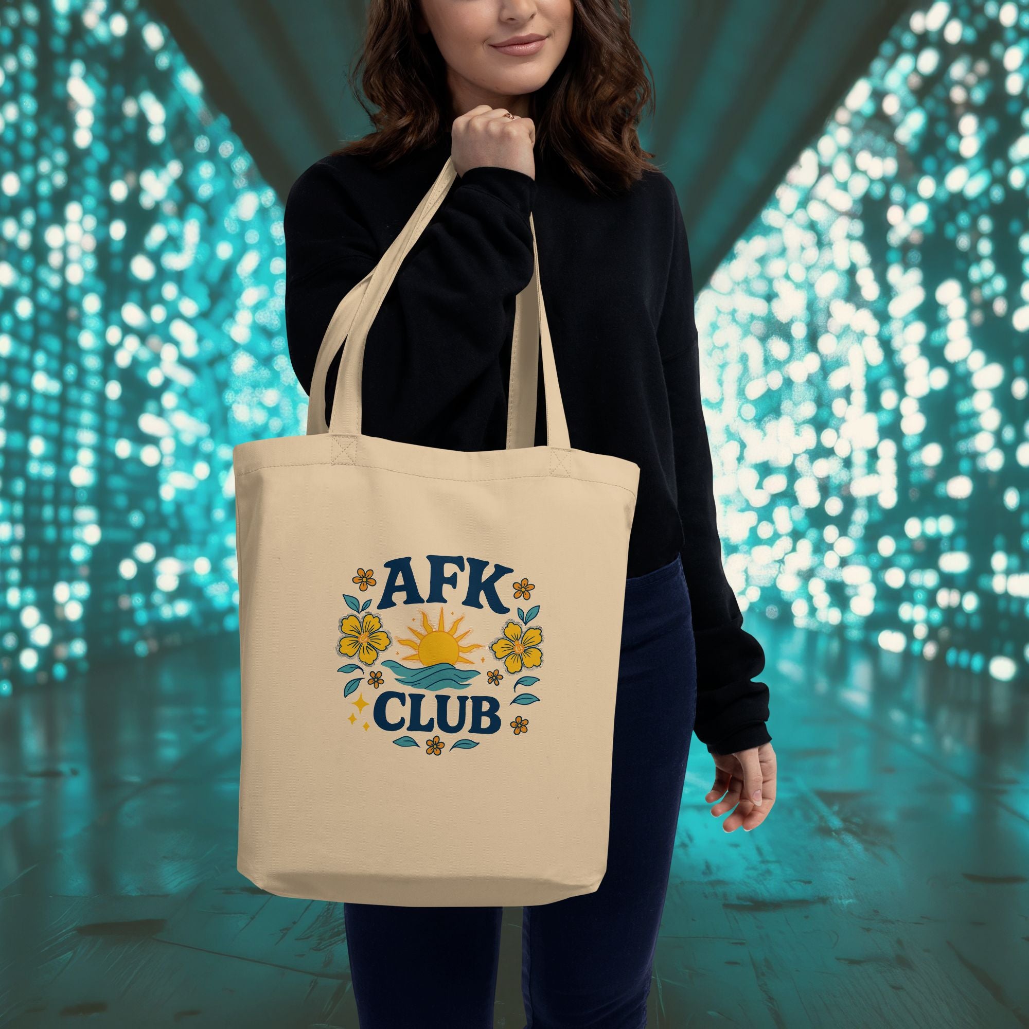 Person holding a beige tote bag with 'AFK Club' design against a blurred light background