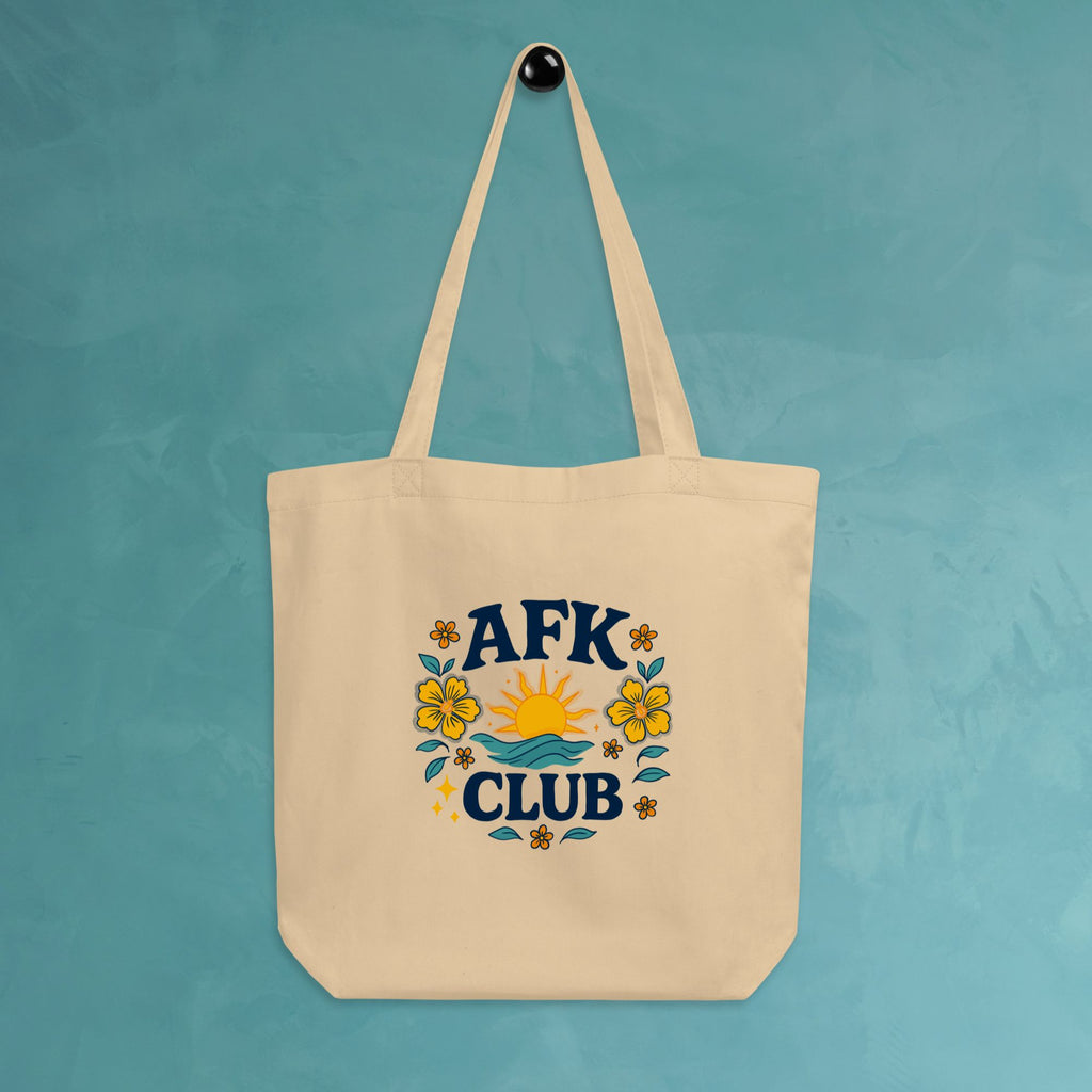 Beige tote bag with 'AFK Club' design hanging on a teal wall.