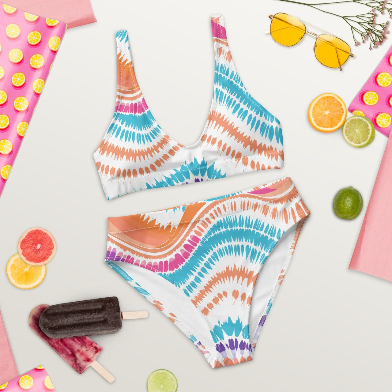 Flat lay front view of ErdeGora’s Crush Waves bikini featuring a high-waisted bottom and a matching V-neck top, both crafted from sustainable recycled materials and adorned with a dynamic, multicolored wave-inspired print.