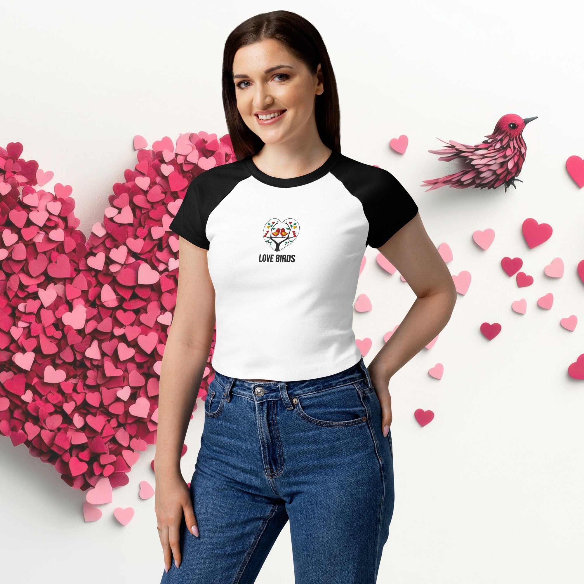 Woman wearing ErdeGora micro rib raglan baby tee front view, white with black sleeves and embroidered Love Birds heart with text, front view.