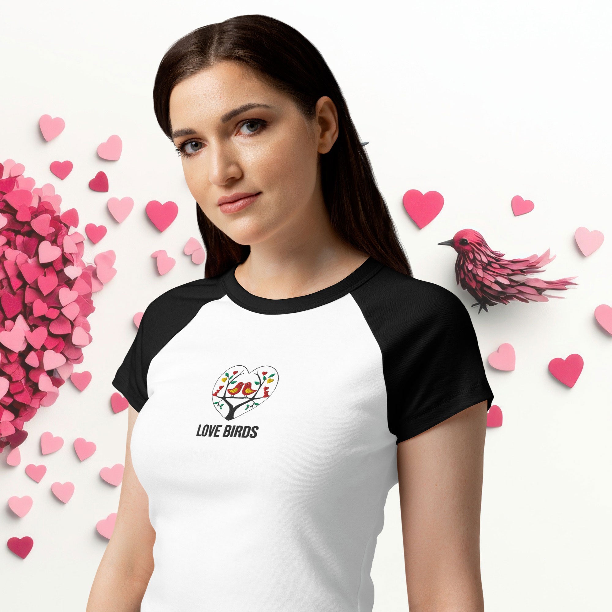 Woman wearing ErdeGora micro rib raglan baby tee front view, white with black sleeves and embroidered Love Birds heart with text, close view.
