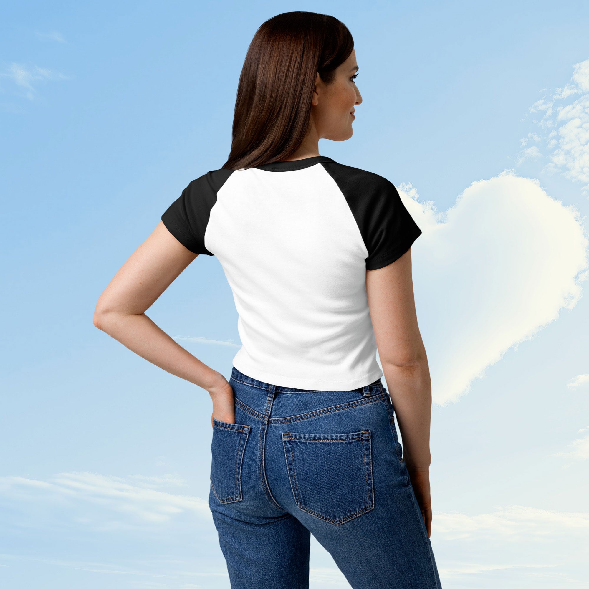 Woman wearing a white and black baseball shirt with a graphic design against a blue sky, back view.
