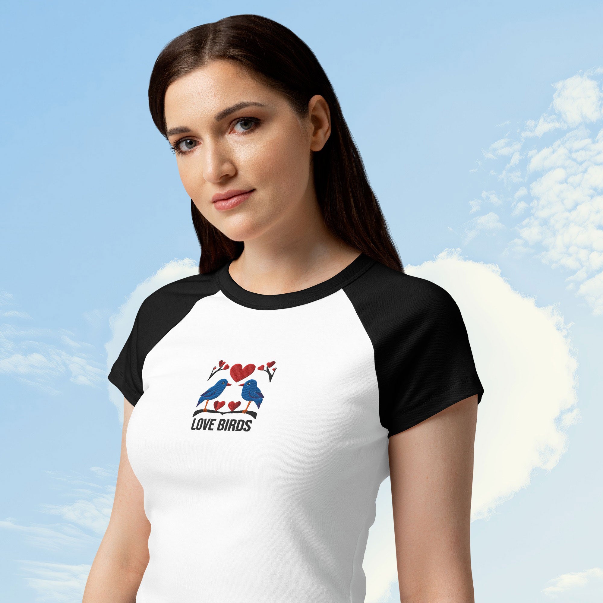 Woman wearing a white and black baseball shirt with 'Love Birds' design against a blue sky background