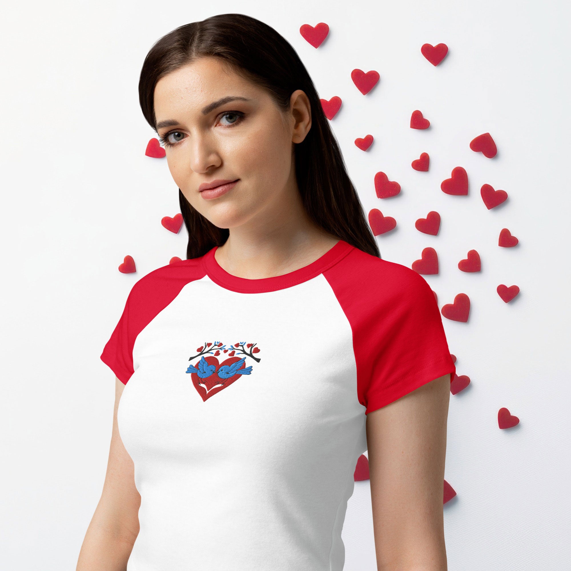 Woman wearing a red and white baseball shirt with a heart design, surrounded by small hearts on a light gray background.