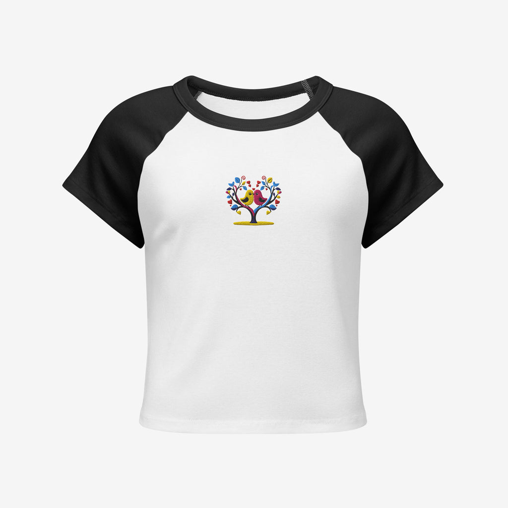 White t-shirt with black sleeves featuring an embroidery design of lover birds on a heart shaped tree on a white background.