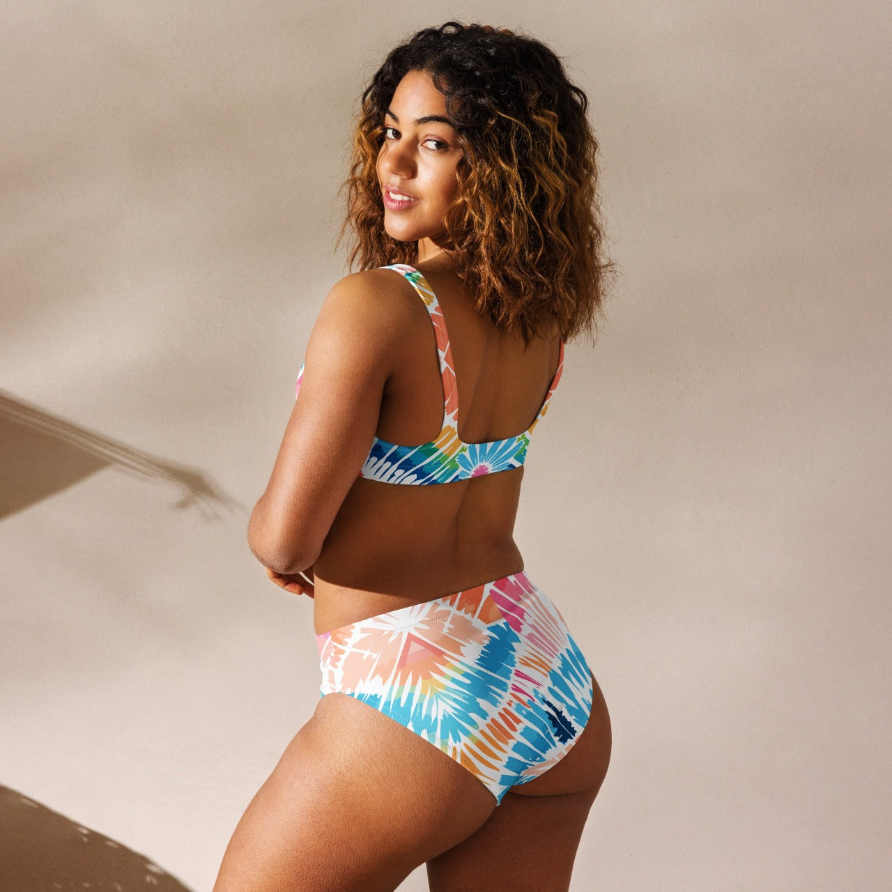 Model presenting the back side of the Recycled High-Waisted Bikini Peachy Saltwater, with a focus on the comfortable high-waist design and dynamic print.