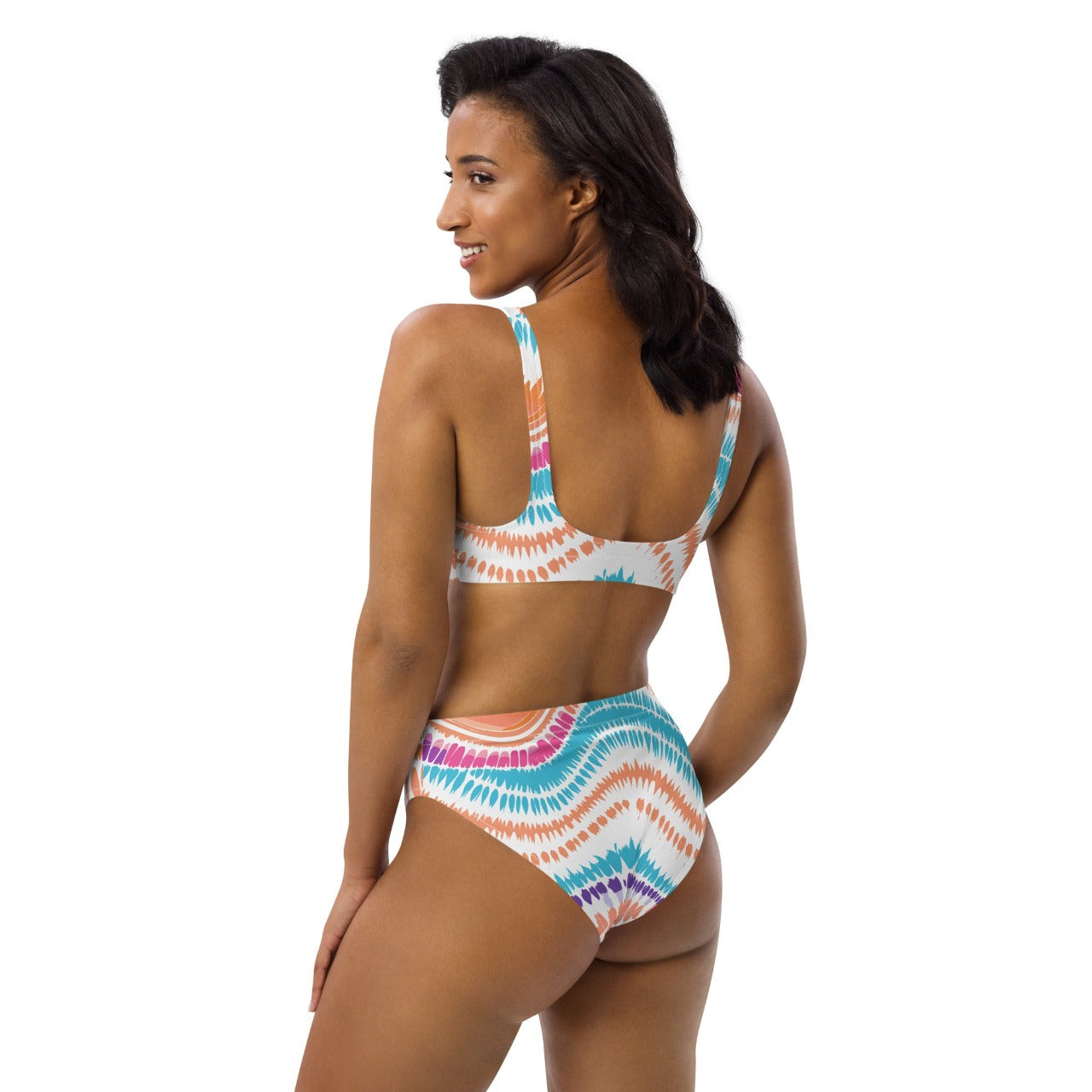 Female model showing a side back view of ErdeGora’s white Crush Waves bikini, highlighting the curve of the high waist and the back cut of the top with the unique wave pattern.