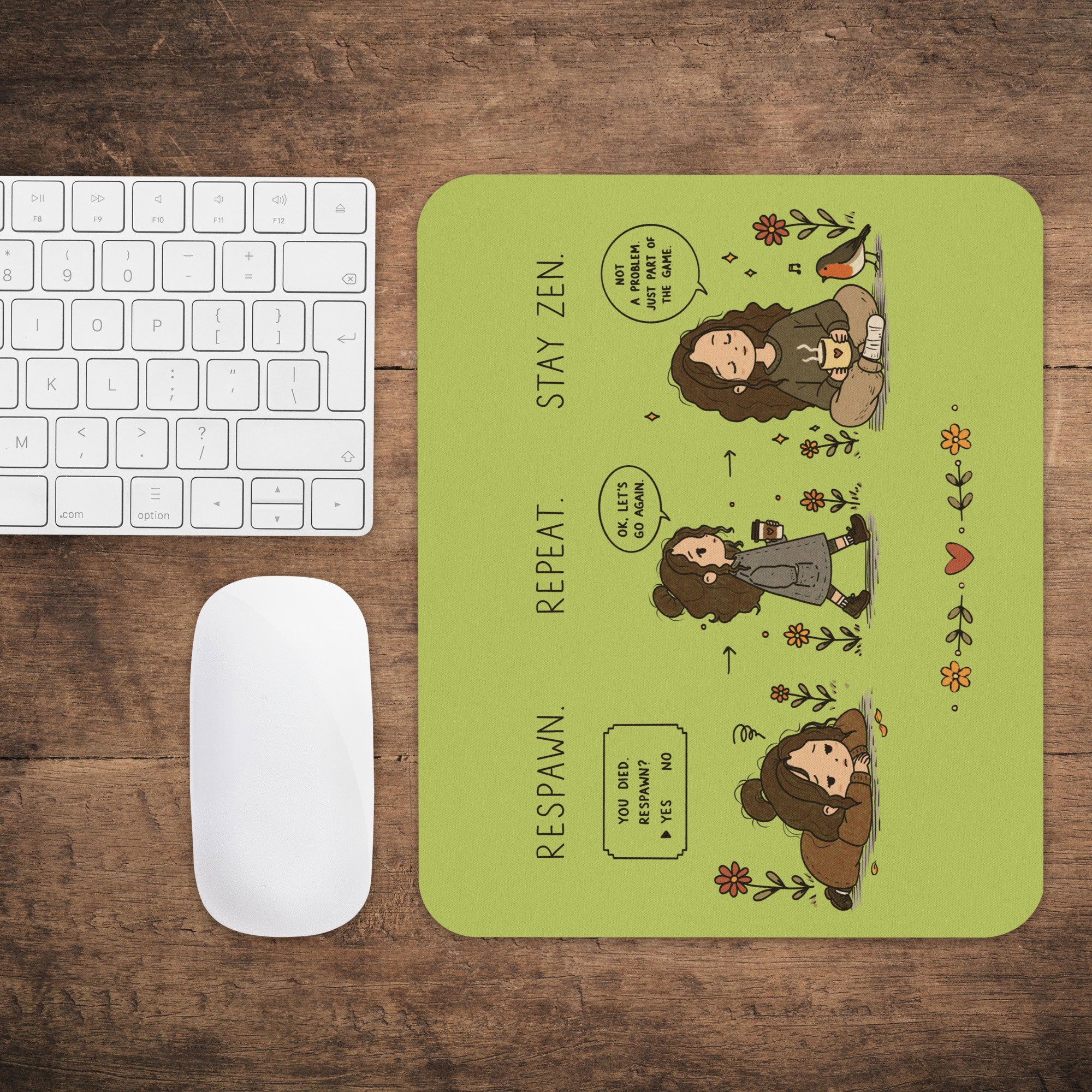 A rectangular mouse pad with rounded corners sits on a wooden desk next to a white keyboard and mouse. The mouse pad has a light olive-green background with a cartoon-style three-panel illustration of a woman labeled 'STAY ZEN', 'REPEAT', and 'RESPAWN', surrounded by small flowers and a bird.