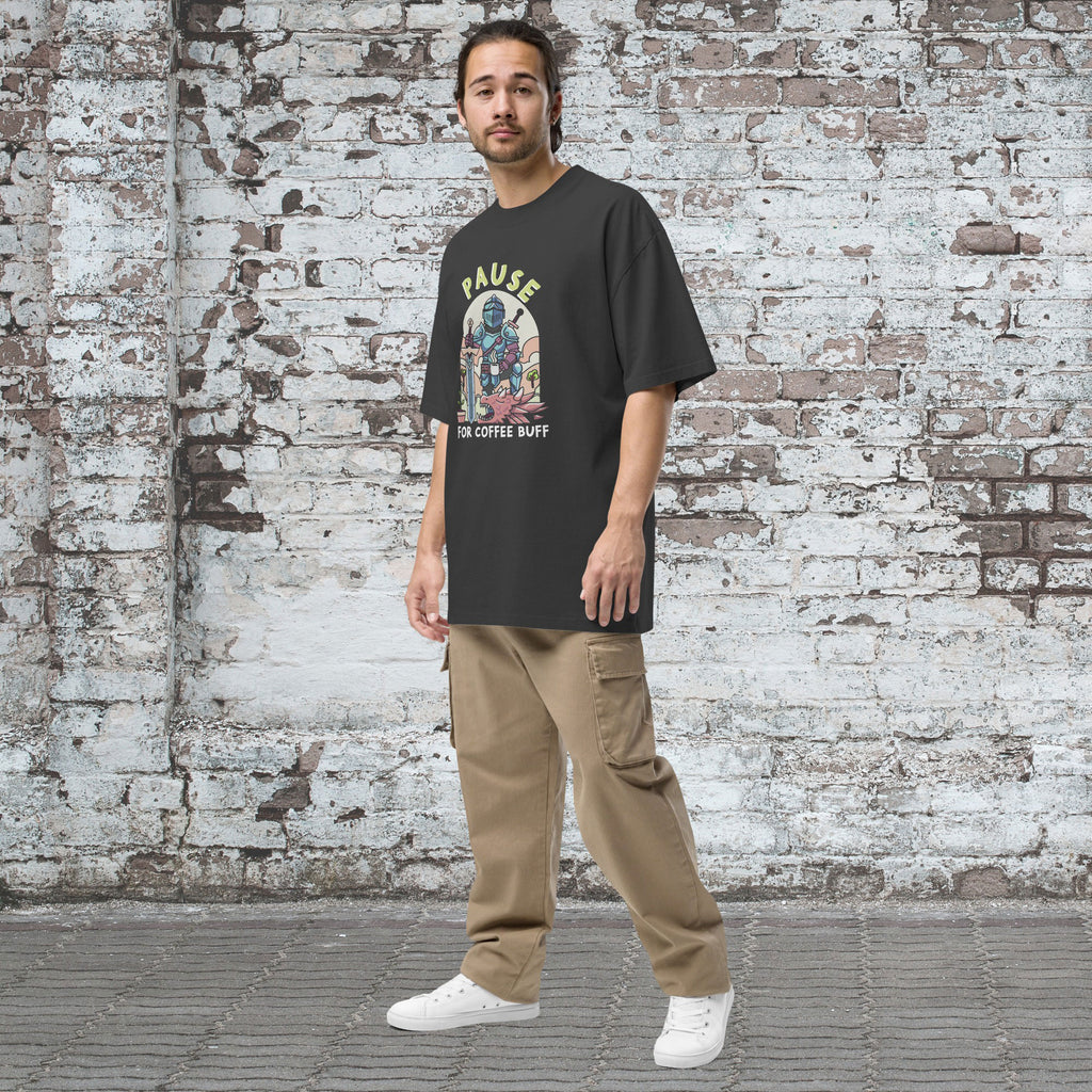 Man wearing a black t-shirt with graphic design and beige pants standing against a textured brick wall.