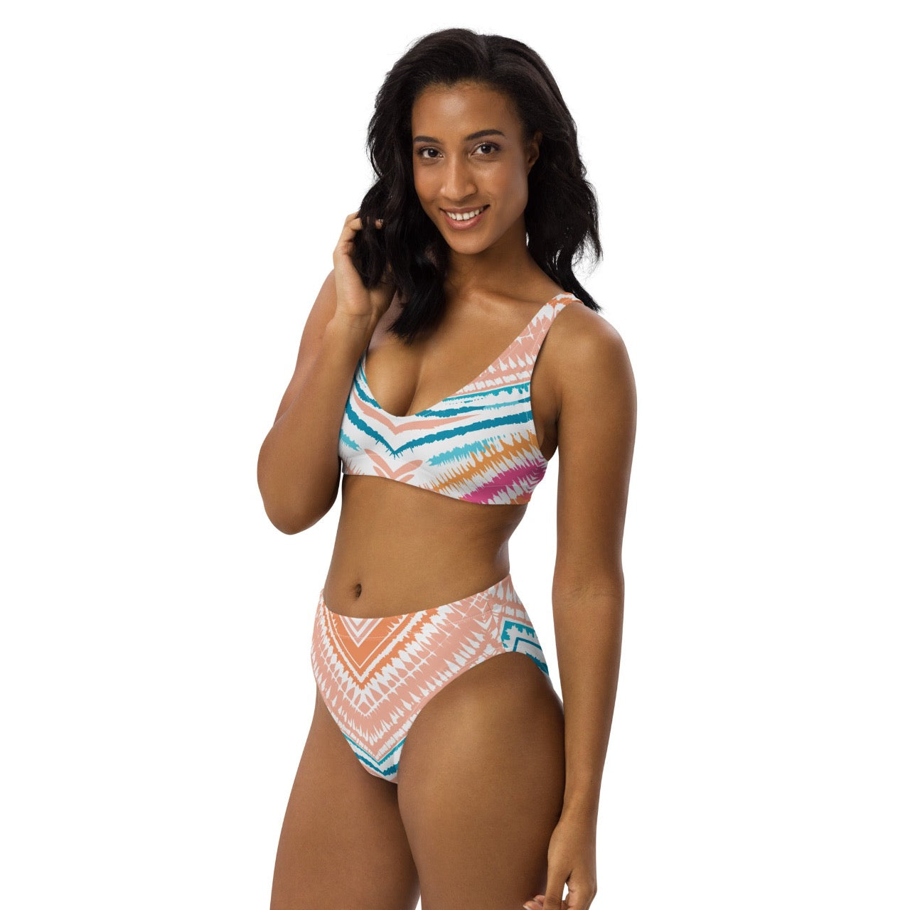 Female model wearing ErdeGora Recycled High-Waist Bikini Peachy Blues Tribal Splash, front-side view, featuring the flattering high-waisted bottom and vibrant tribal print top.