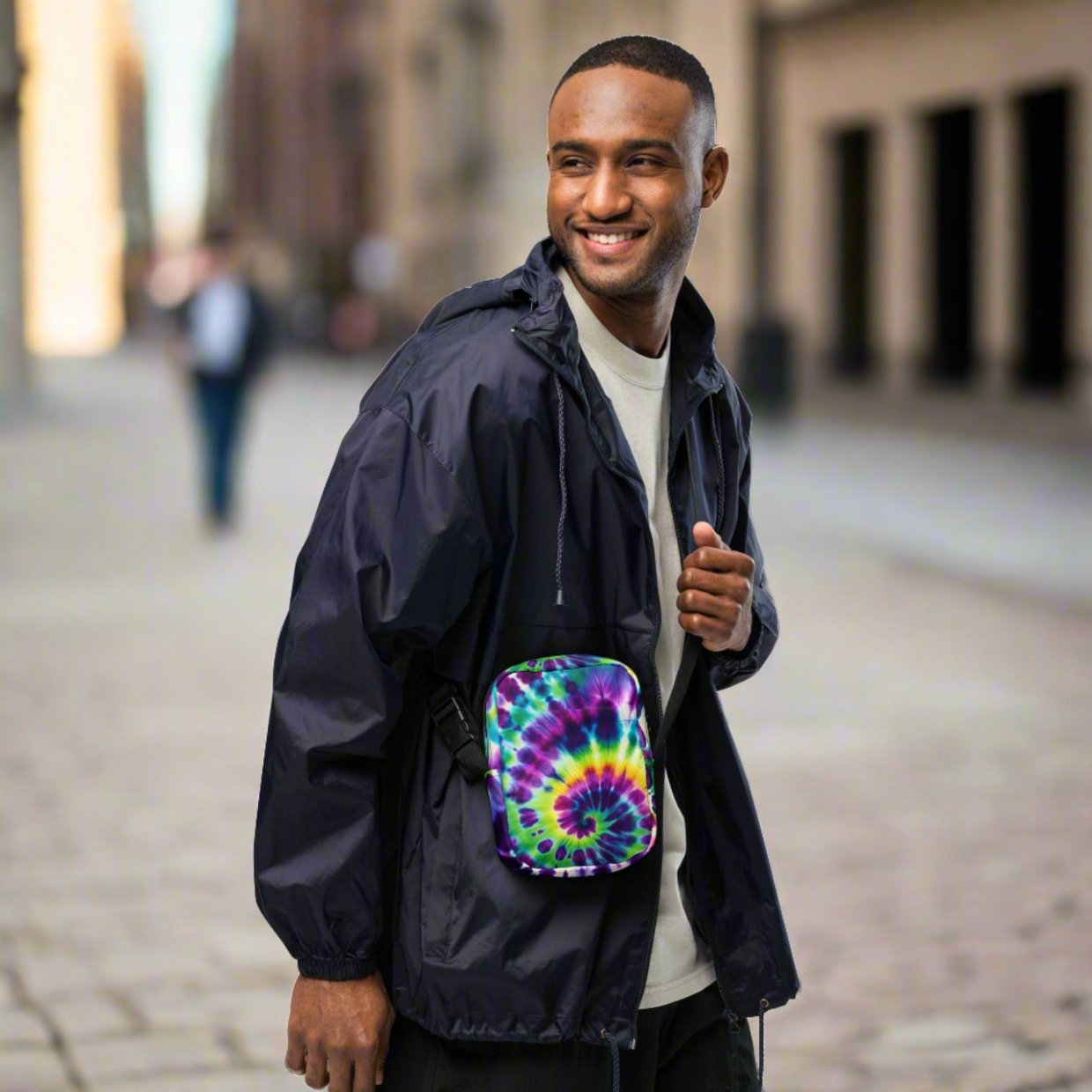 Man wearing a Utility Crossbody Bag in Tie-Dye Fusion, featuring a vibrant tie-dye pattern, adjustable strap, and roomy pockets, perfect for city escapes..