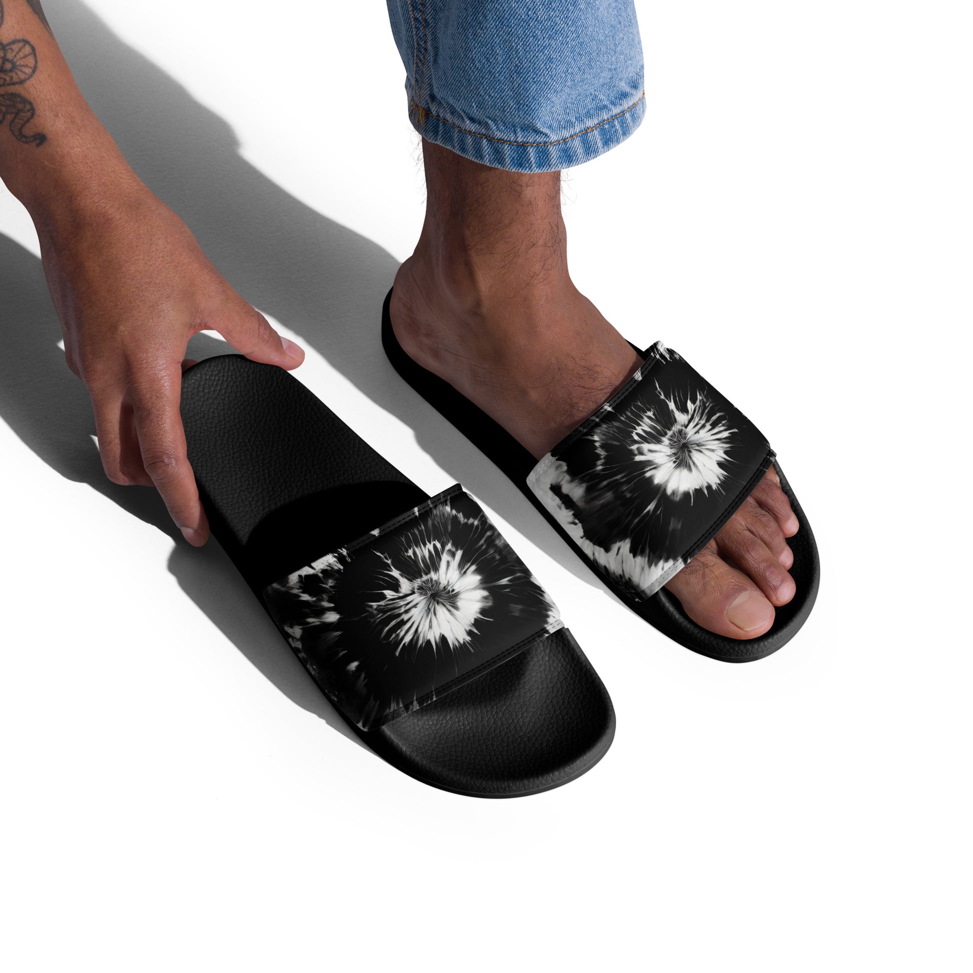 Man wearing Men’s Slides in Monochrome Burst, featuring a striking black and white tie-dye design and cushioned footbed, perfect for summer activities.