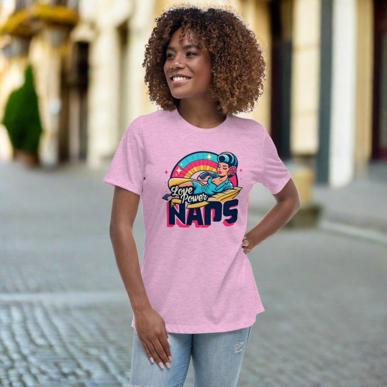 Woman smiling in a 'Love Power Naps' graphic t-shirt with vibrant retro design on pink background - a casual and comfy statement piece.